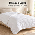 Piumino Bamboo Light bianco da 100 g/m² aperto sul letto con un risvolto morbido