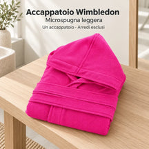 Accappatoio Wimbledon Fucsia piegato su una panca in un bagno neutro, con cappuccio e cintura visibili.