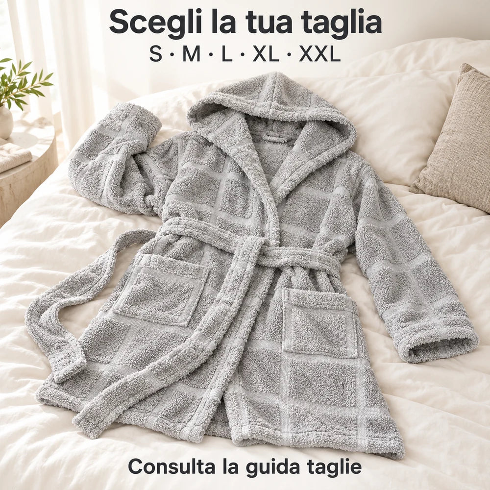 Accappatoio Zero Twist Perla con cappuccio, in spugna a grandi riquadri, disteso su un letto con cappuccio aperto e cintura sciolta.