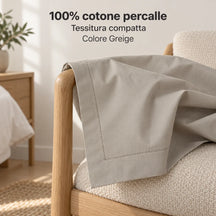 Federa Greige vuota parzialmente aperta e drappeggiata sul bracciolo. Foto illustrativa: Greige. Guanciali, arredi e accessori esclusi.