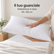 Guanciale in lana Bianco sostenuto dalle braccia e leggermente compresso. Arredi e accessori esclusi.